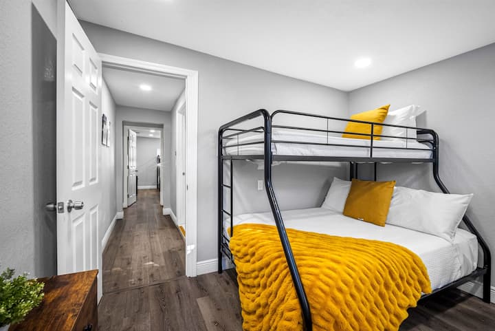 Une chambre confortable avec des lits superposés, un éclairage doux, une décoration moderne et des touches de jaune vif pour créer une ambiance accueillante.