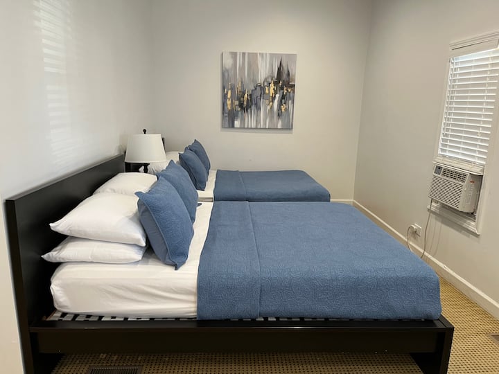 ห้องพักสะอาดพร้อมเตียงคู่ ผ้าปูที่นอนสีฟ้า เครื่องปรับอากาศ และการตกแต่งที่ทันสมัย