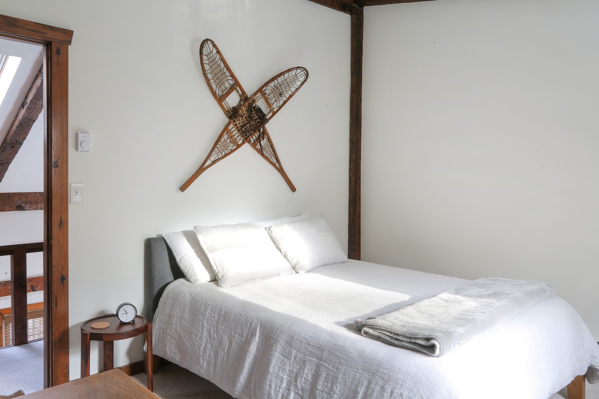 The upstairs snowshoe bedroom has a queen bed with luxury linen bedding and features art representative of winter recreation in the Catskills.