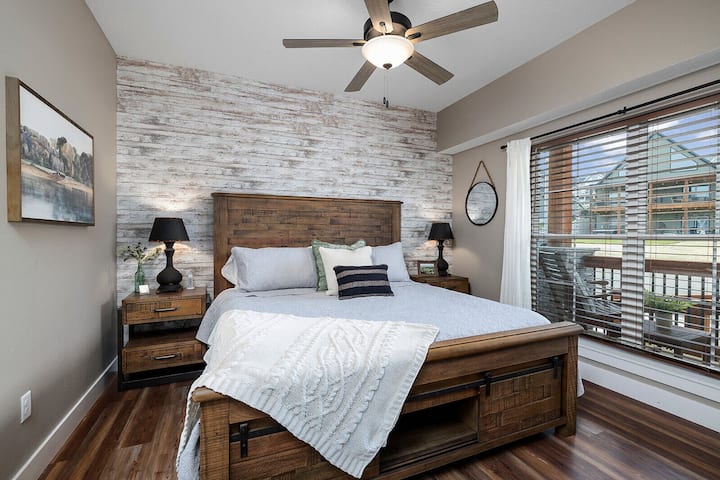 Спалня с голямо двойно легло на основното ниво със съседна баня за хора с увреждания