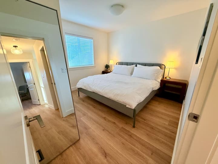 Another upstairs king bedroom, with a dresser, mirror and bedside lighting.