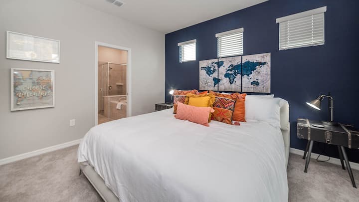 غرفة نوم رئيسية بسرير كبير وحمام ملحق بالطابق السفلي