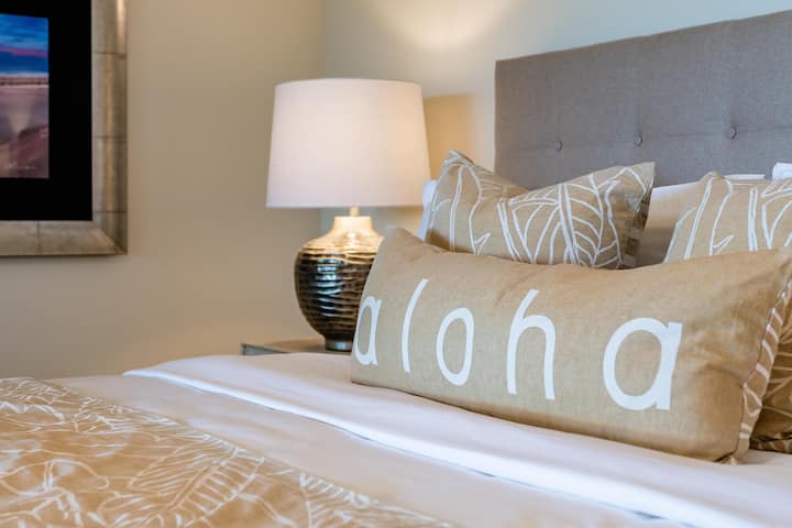 Útulná posteľ s vankúšom, vzorovanou posteľnou bielizňou a lampou.