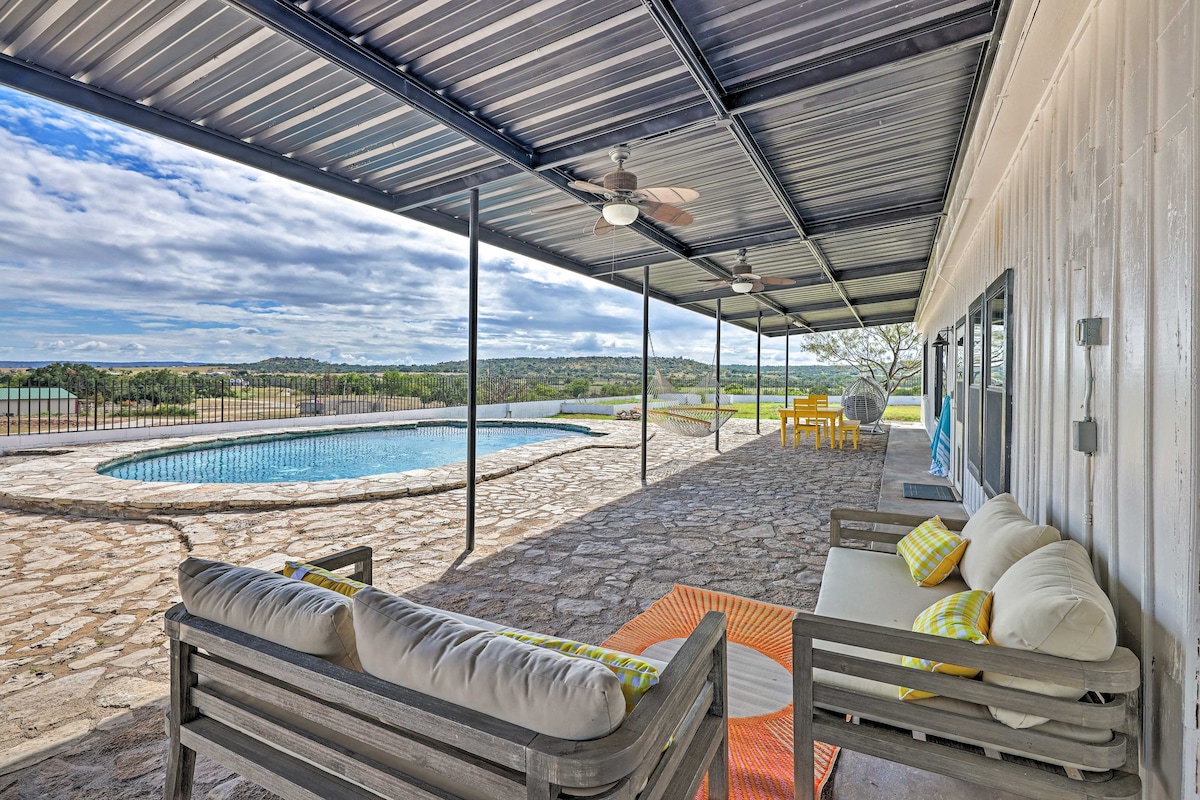 A covered outdoor patio features comfortable seating options, including a sofa with colorful cushions. A dining table is visible along with a private pool that overlooks the valley. The expansive area is designed for relaxation and enjoyment in a tranquil setting.
