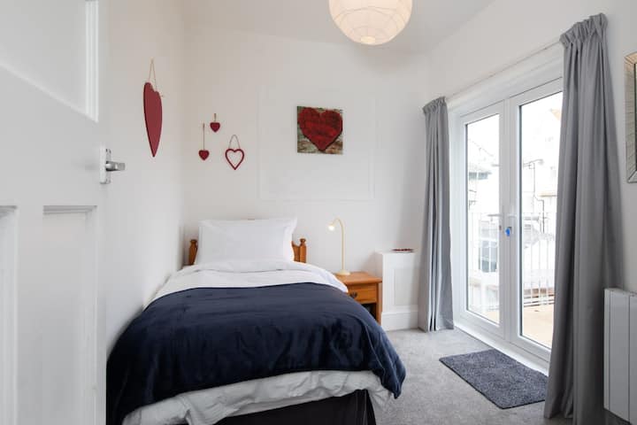 Chambre deux avec un lit simple et accès au balcon privé par les portes doubles