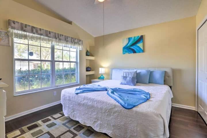 سرير متوسط الحجم ونافذة كبيرة ورفوف مزخرفة. تتميز الغرفة بألوان مريحة مع لمسات زخرفية زرقاء وبيضاء.