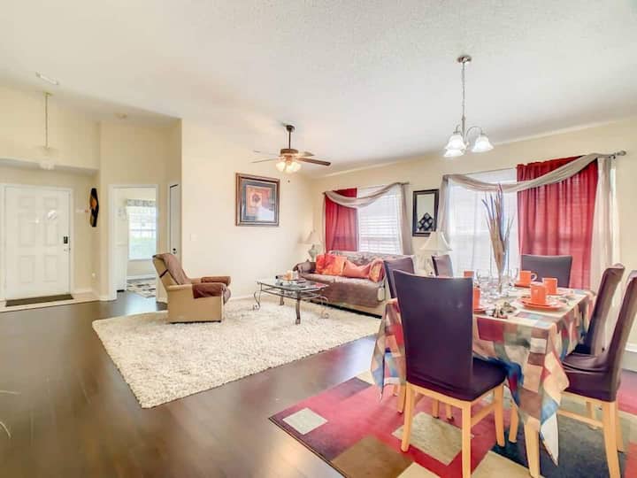 تتميز بمنطقة المعيشة ومنطقة لتناول الطعام. تحتوي منطقة المعيشة على أريكة وكرسي بذراعين وسجادة، بينما تحتوي منطقة تناول الطعام على طاولة معدة لتناول وجبة.