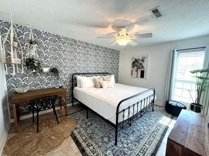 Boho bedroom w/ accent wall, desk, and bright natural light