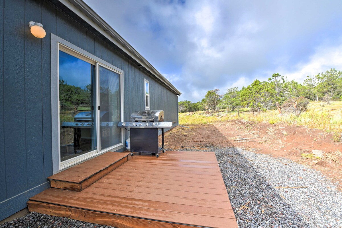 An outdoor deck is showcased, featuring a gas grill positioned next to sliding glass doors. The area is surrounded by gravel and natural landscaping, with open space visible in the background, allowing for views of the surrounding terrain.