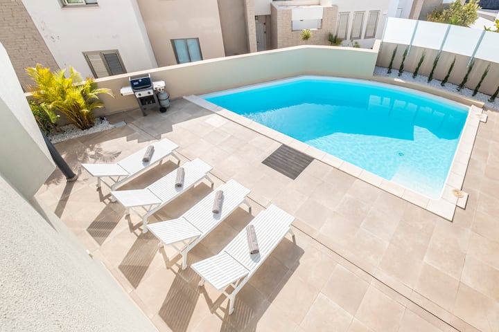 Heated pool area with sun loungers and golf course views