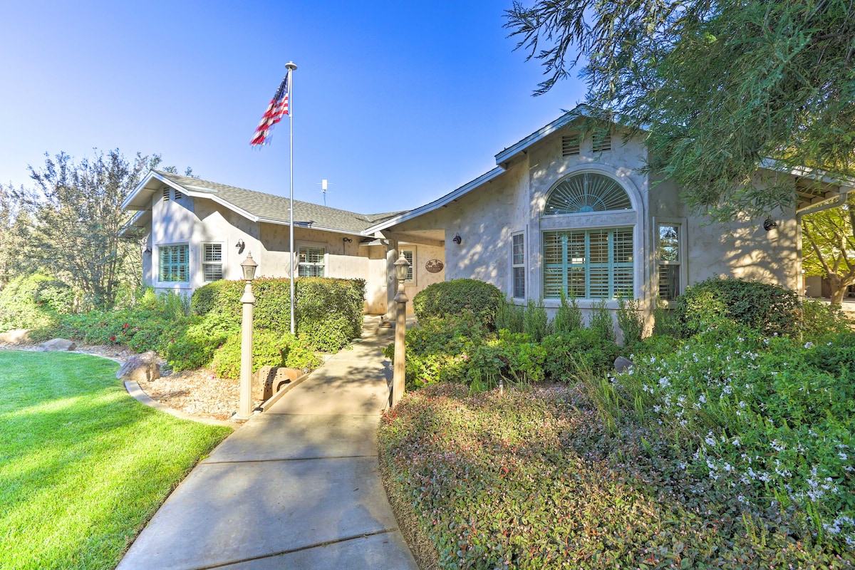 The exterior of the home showcases a well-maintained pathway leading to the entrance, framed by lush greenery and colorful flowers. A flag gently waves in the breeze, and the soft tones of the building harmonize with the surrounding landscaping.