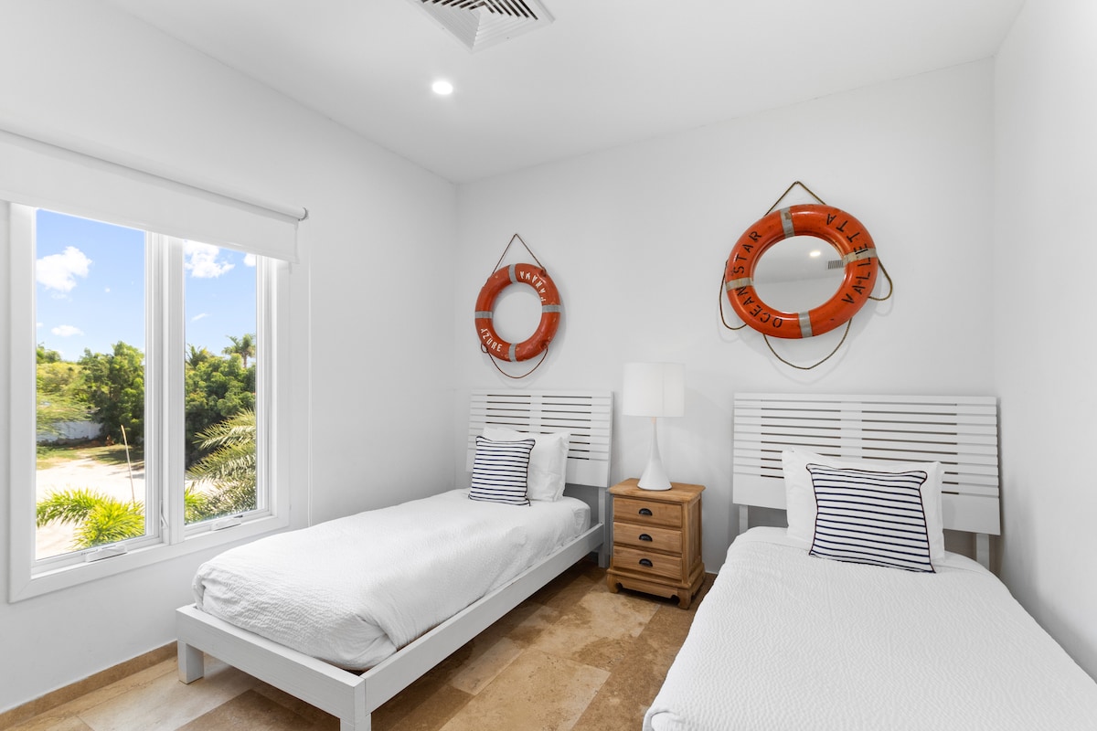 חדר שינה יפהפה בווילה בנורד ארובה - 2 מיטות יחיד נוחות - חדר מעוצב באלגנטיות - קירות צבועים יפהפיים עם קישוט - מנורות שולחן מלכותיות - מצעים נקיים ומסודרים - חלונות גדולים עם נוף יפהפה