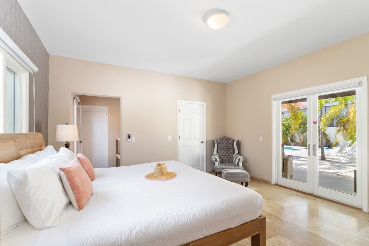 חדר שינה מרהיב בווילה בנורד ארובה - מיטה זוגית נוחה - חדר מעוצב באלגנטיות - קירות צבועים יפהפיים עם קישוט - מנורות שולחן מלכותיות - מצעים נקיים ומסודרים - חלונות גדולים עם נוף יפהפה - טלוויזיה ונטפליקס זמינים