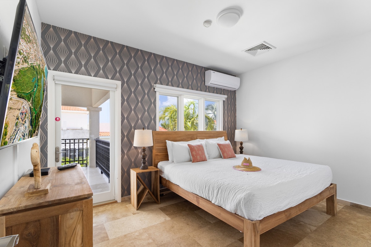 חדר שינה יוצא מן הכלל בווילה בנורד ארובה - מיטה זוגית נוחה - חדר מעוצב באלגנטיות - קירות צבועים יפהפיים עם קישוט - מנורות שולחן מלכותיות - מצעים נקיים ומסודרים - חלונות גדולים עם נוף יפהפה - טלוויזיה ונטפליקס זמינים