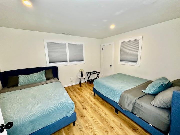 - Amplio dormitorio con dos camas de felpa, perfecto para familias o amigos que comparten un espacio.
- La ropa de cama azul suave y las persianas opacas crean un ambiente relajante para una gran noche de sueño
- Los suelos de madera y la decoración minimalista ofrecen una sensación fresca y espaciosa en todas partes.