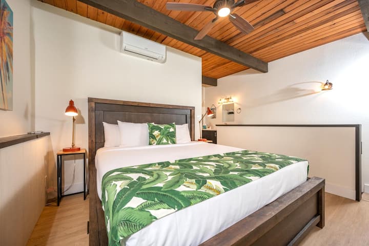 ห้องนอนใหญ่สไตล์ลอฟท์ที่หรูหราพร้อมเตียงคิงไซส์ งานศิลปะเกาะ คานเปิดโล่ง และแสงนุ่มจากระเบียงวิวราว