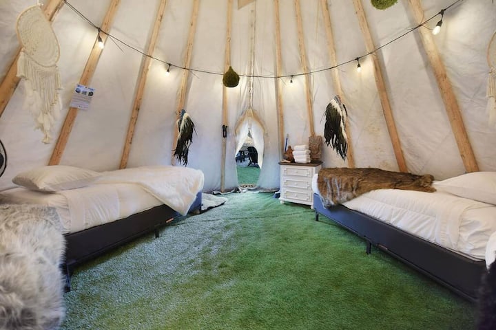 სოფლური ტიპის კარვის მყუდრო ინტერიერი ორი ერთადგილიანი საწოლითა და რბილი განათებით.