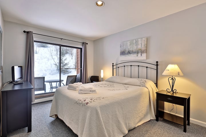 Მთავარი საძინებელი 152 × 203 სმ საწოლით.  Უამრავი ბუნებრივი განათება, შუშის გასრიალებული კარები, რომლებიც პატიოსკენ იღება (შესანიშნავია სეზონების უმეტესობისთვის)