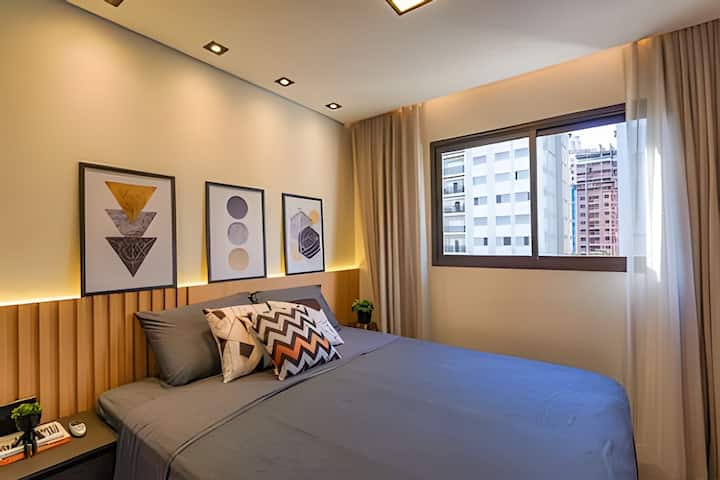 Quarto aconchegante e sofisticado. Possui ar-condicionado e cortinas blackout, ideal para descanso absoluto. A iluminação indireta cria um clima relaxante e o armário oferece praticidade para uma estadia confortável e tranquila.