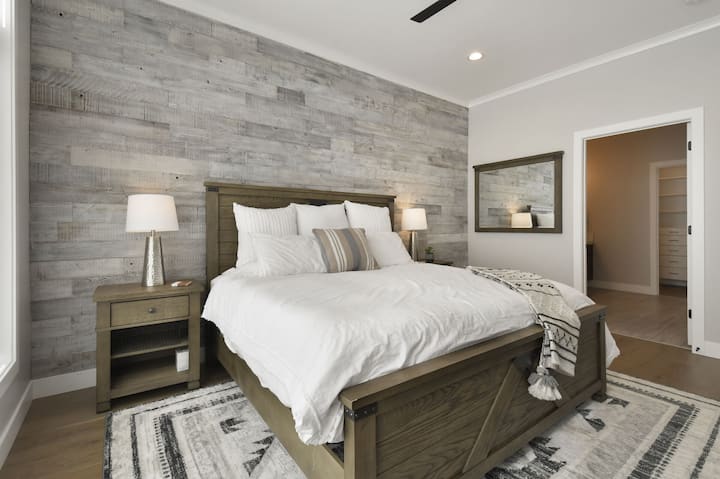 غرفة نوم أساسية مع جدار خشبي وألوان محايدة مريحة.