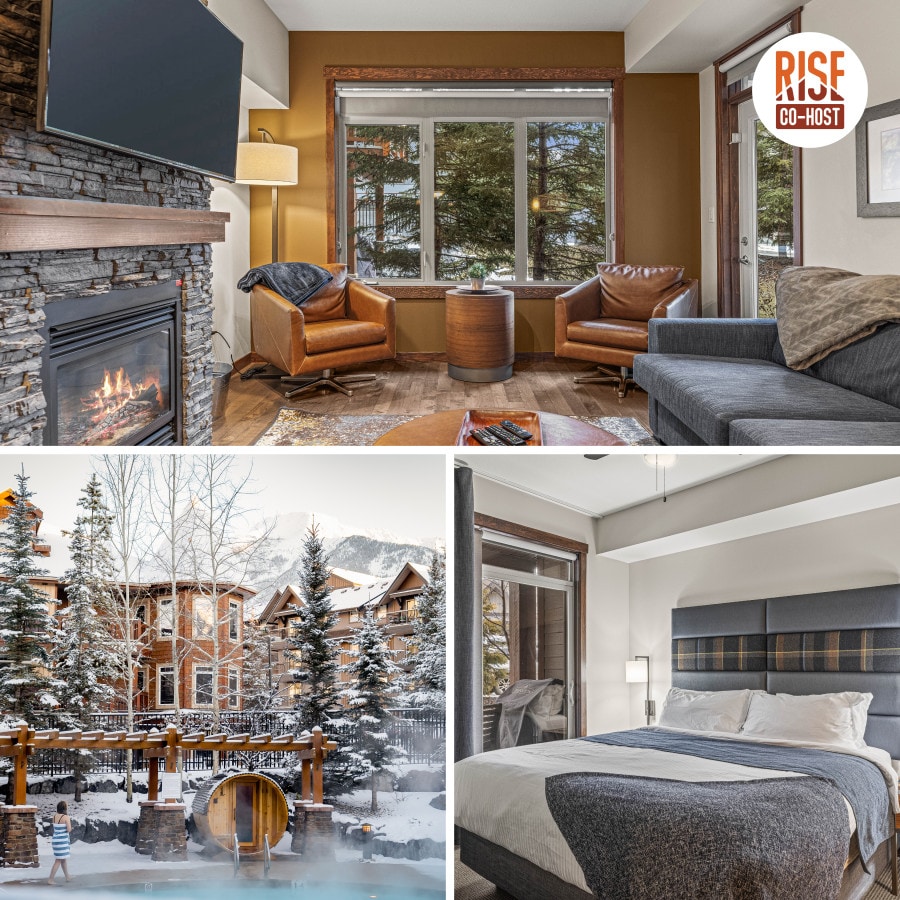 A cozy living area features a stone fireplace, two brown leather chairs, and a grey sofa with a coffee table. Large windows provide views of the surrounding trees, creating a warm ambiance.
