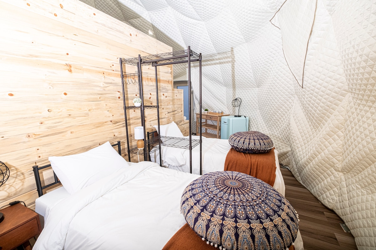 Tucked behind a wooden divider wall, these cozy twin beds offer privacy and a serene sleeping space. The geodome design adds a unique touch to this peaceful retreat
