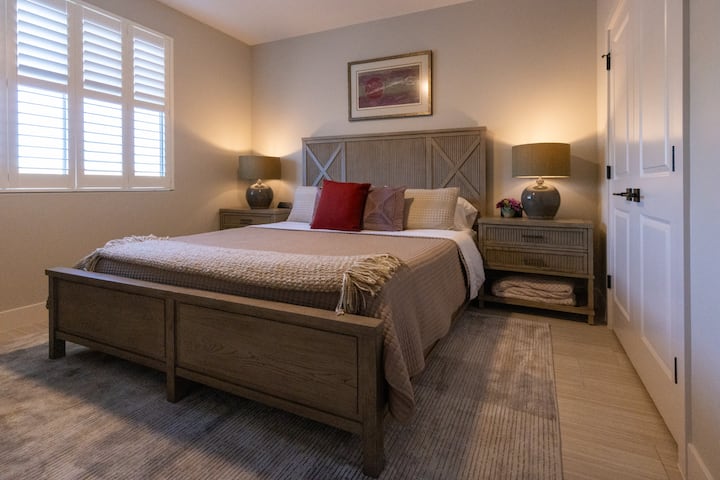 Chumba cha wageni kilicho na kitanda cha kifahari, televisheni na kabati la nguo.