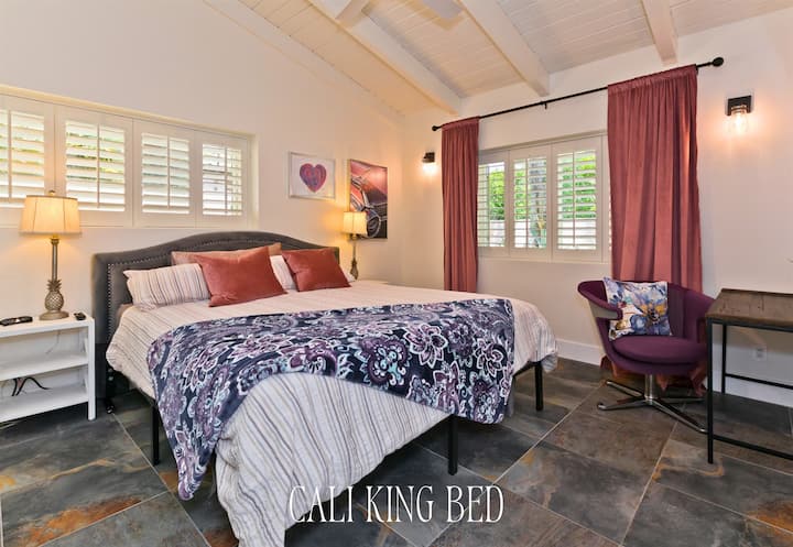 เตียงคิงไซส์สไตล์แคลิฟอร์เนีย หมอนนุ่มๆ และโทนสีเข้มทำให้ห้องสวีทนี้เป็นสถานที่พักผ่อนที่อบอุ่นและมีความโรแมนติก