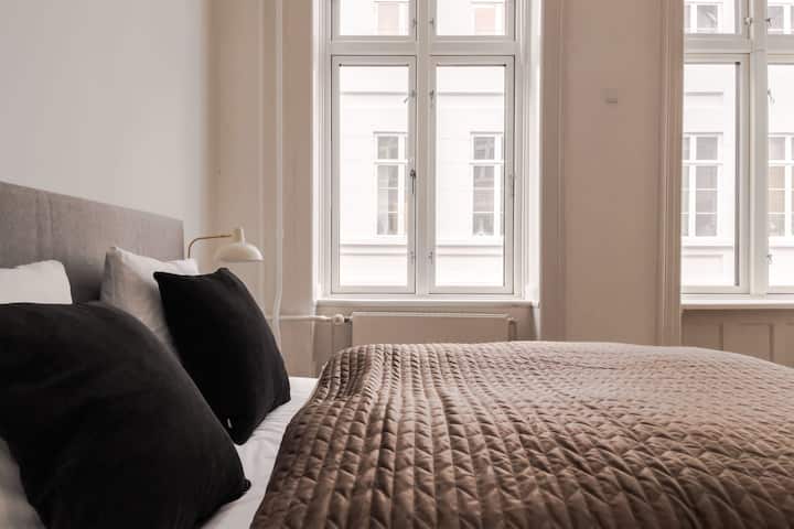 Дизајнот на спалната соба е елегантен и модерен, со фокус на удобност и релаксација. Комбинацијата од природна светлина, меки текстури и стилски декор создава простор кој е привлечен и мирен.