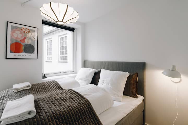 En el centro de los dormitorios te espera una cómoda cama doble, con un elegante y elegante marco de cama gris que añade un toque sofisticado al espacio.