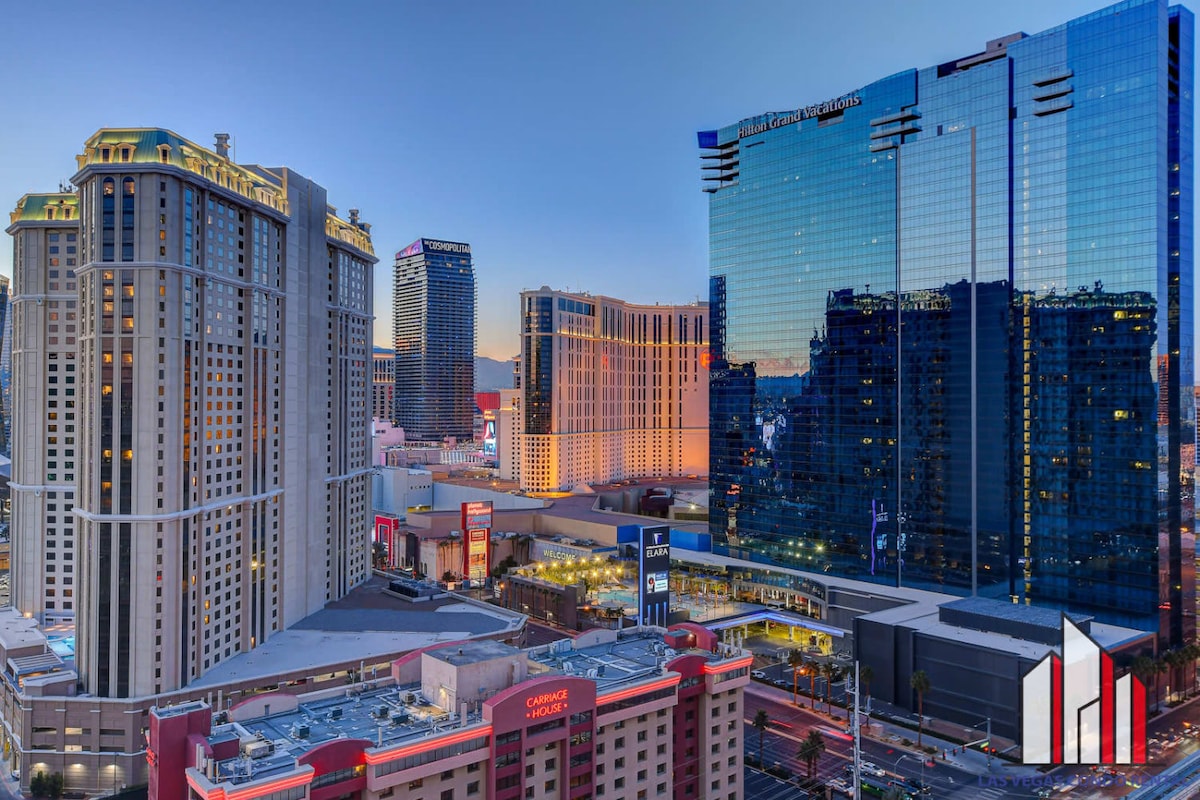 A panoramic view of the Las Vegas Strip is captured at dusk, showcasing illuminated buildings and vibrant city life. The reflective glass façades of modern towers contrast with classic architecture, highlighting the dynamic character of the city. The sky transitions from orange to deep blue, framing the scene.