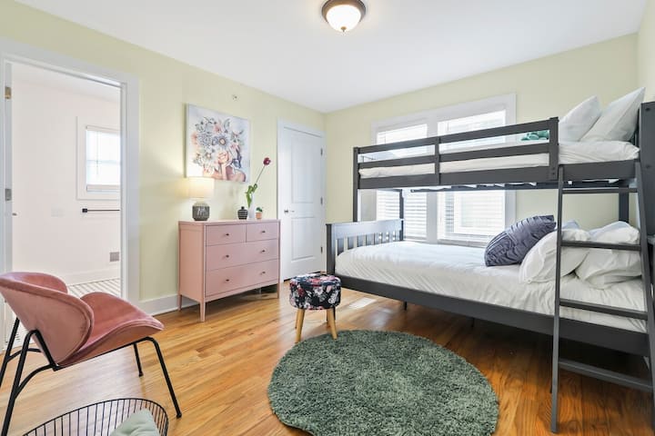 1st Floor Bunk Bedroom-This charming bunk room provides flexible sleeping arrangements with a sturdy twin-over-twin bunk bed, perfect for kids or a group of friends. The room features playful decor, including a dusty pink dresser and a cozy chair