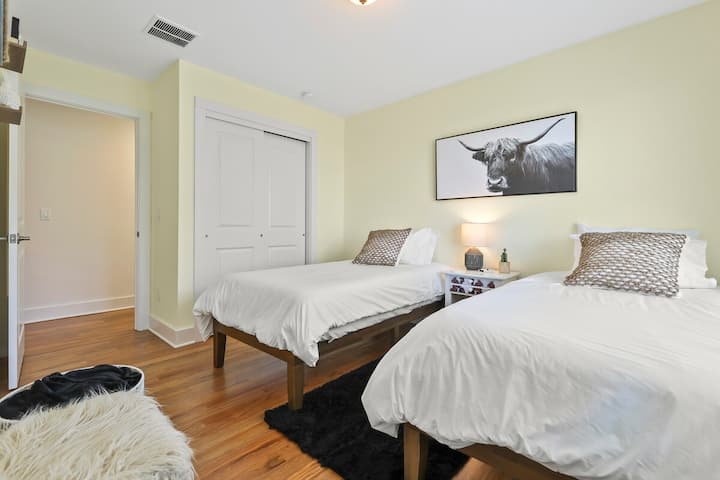 1st Floor Twin Bedroom-This bright and cozy bedroom features two comfortable twin beds, perfect for friends or family traveling together. Enjoy the unique, modern style, highlighted by the striking highland cow artwork above the bed.