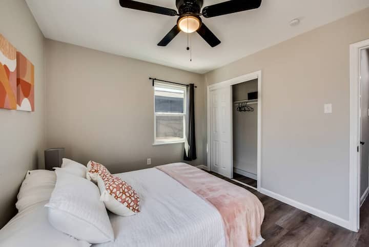 ห้องนอนนี้มีเตียงหรูหราพร้อมผ้าปูที่นอนสีขาวและรายละเอียดสีชมพู พัดลมเพดานช่วยให้มั่นใจได้ถึงความสะดวกสบายในขณะที่ตู้เสื้อผ้าแบบเปิดช่วยเพิ่มพื้นที่ใช้สอยได้มากที่สุด โต๊ะข้างเตียงที่ทันสมัยและศิลปะบนผนังที่เป็นนามธรรมเพิ่มความสง่างามสมัยใหม่