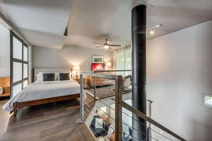 Al llegar a la parte superior de los escalones, disfruta de una vista acogedora del dormitorio del loft, donde una cómoda cama vestida con lujosas sábanas de algodón egipcio te invita a relajarte y relajarte con estilo.