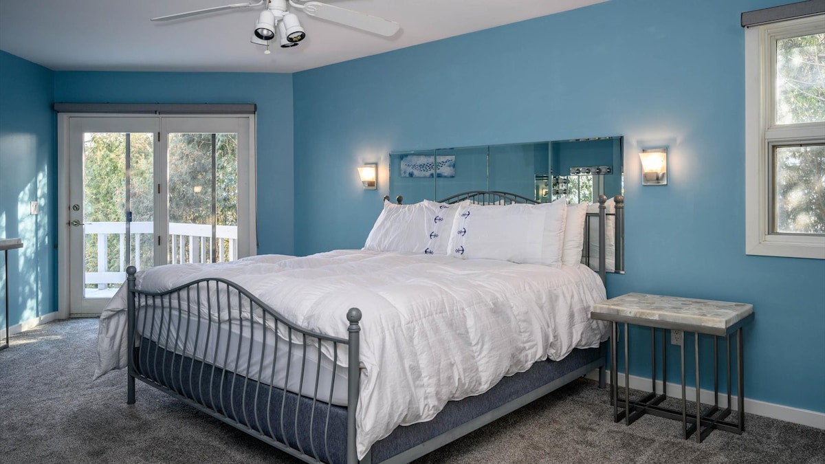 Lujosa cama con puerta que conduce a la cubierta envolvente. Despierta y disfruta de hermosas vistas al lago.