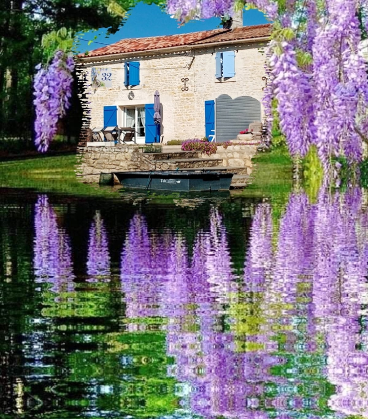 A charming stone house with blue shutters is set beside a serene lake, reflected in the water below. Wisteria blooms hang gracefully from above, adding a touch of color to the peaceful landscape.