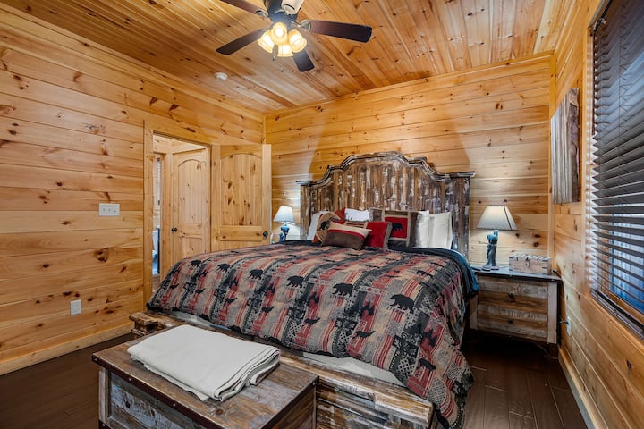 غرفة النوم الرئيسية – غرفة نوم مريحة في جبال سموكي مع أثاث خشبي ريفي، وتصميم داخلي من الخشب الدافئ، وسرير كينج مثالي للاسترخاء بعد مغامرات بيجون فورج.