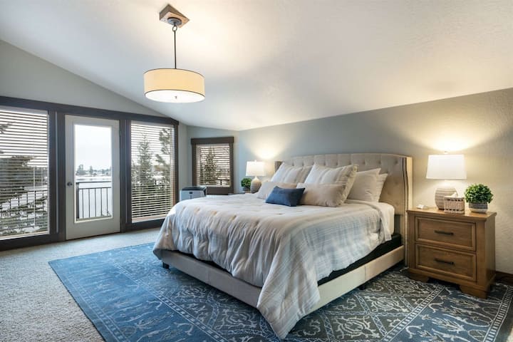 Chumba kikuu cha kulala cha ngazi ya juu kilicho na kitanda cha ukubwa wa kifalme na bafu kuu linaloangalia ziwa.