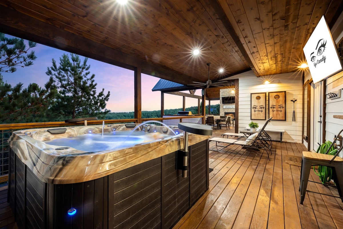 An inviting outdoor hot tub is situated on a wooden deck, surrounded by a spacious area for relaxation. Soft lighting illuminates the space, creating a serene atmosphere with panoramic views of the surrounding nature. Comfortable seating options are available nearby for unwinding.