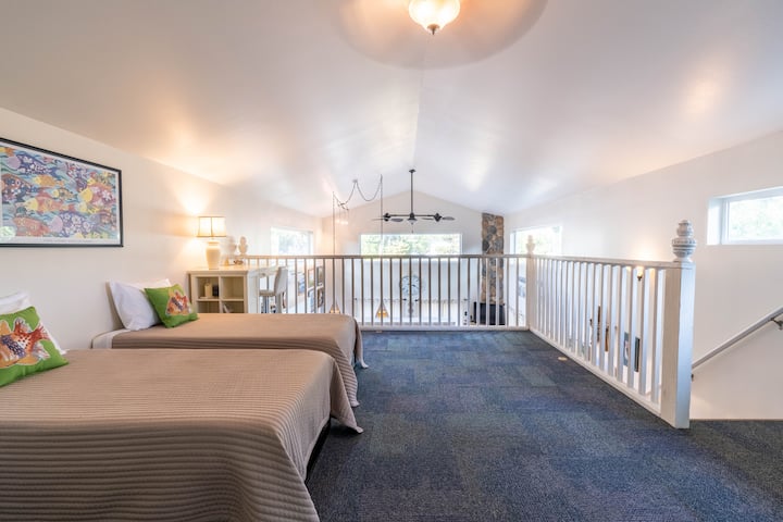 Potkrovlje na katu ima dva kreveta za jednu osobu i radni prostor s pogledom na glavni dnevni boravak. Kreveti za jednu osobu mogu se lako spojiti kako bi se napravio jedan veliki bračni krevet. Fotografija je snimljena sa stražnjih vrata na gornjem katu.