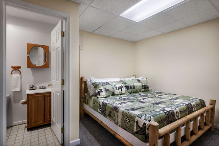 Suite privada de nivel inferior con cama tamaño king y baño completo adjunto, ideal para parejas que desean espacio y privacidad adicionales.
