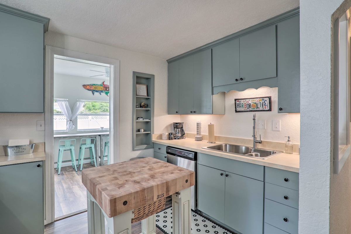 The kitchen features a modern design with light blue cabinetry and stainless steel appliances. A butcher block island serves as a central workspace, while natural light enters from a nearby window. The space is organized, providing a welcoming atmosphere for meal preparation.