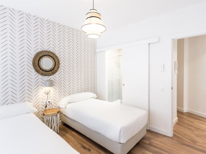 Dormitorio con dos camas individuales y baño en suite.