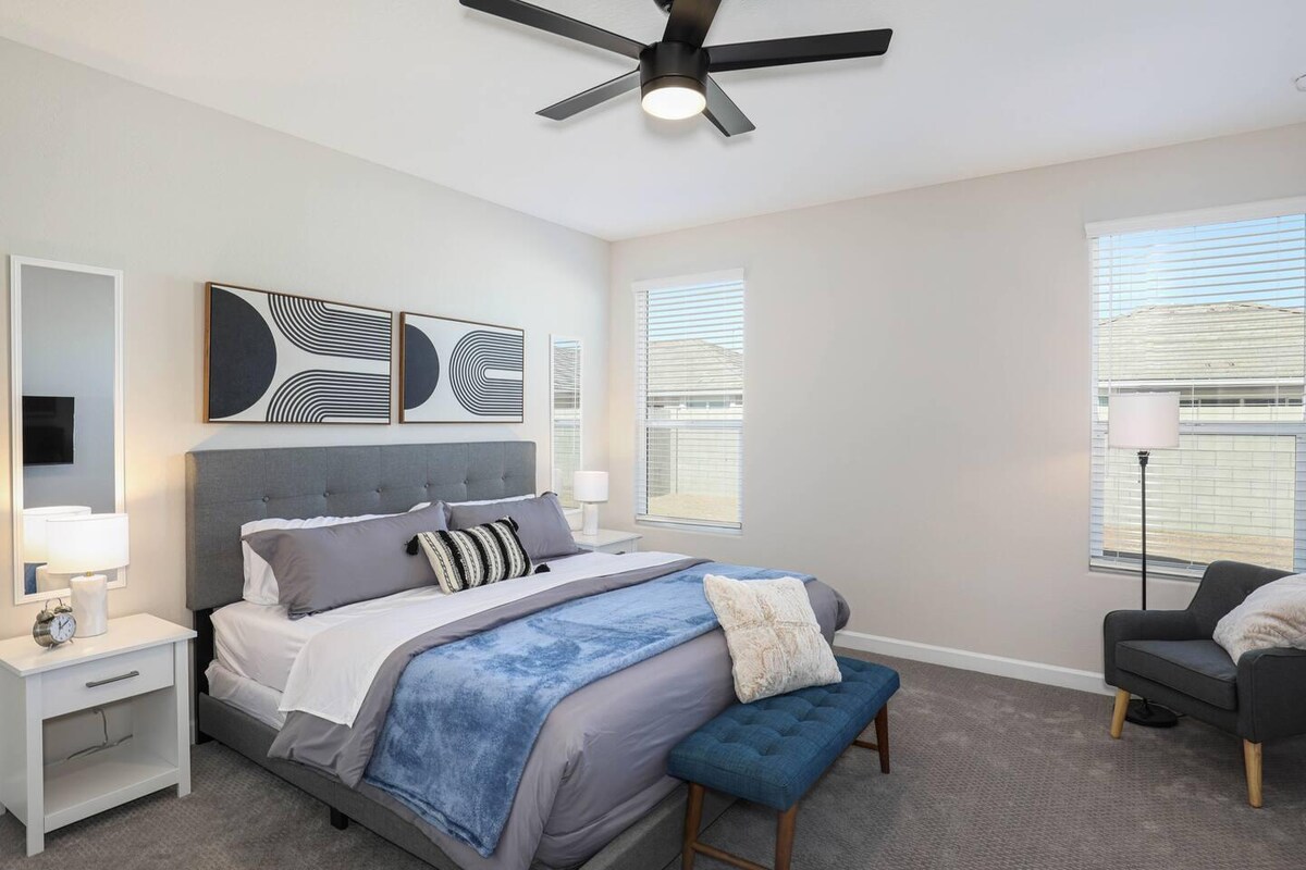 Елегантна главна спална соба со брачен кревет, удобен простор за седење и големи прозорци со природна светлина