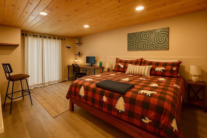 This lower level bedroom has a desk, chair & printer, a king bed, two side tables and a Smart TV