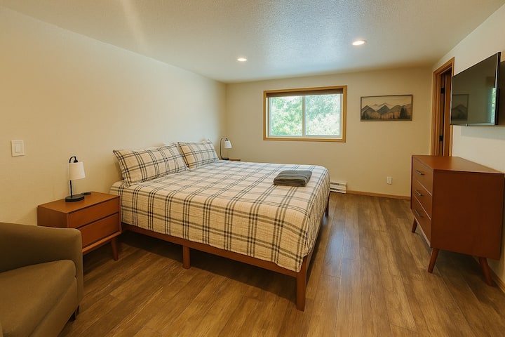 This lower level bedroom has a king bed, a chair, two side tables, smart TV and dresser. There is also an adjoining bathroom.