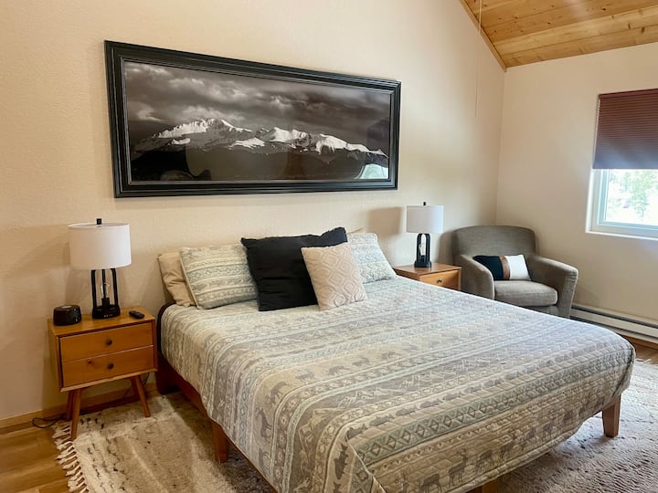Master bedroom has a king bed, two side tables and a chair