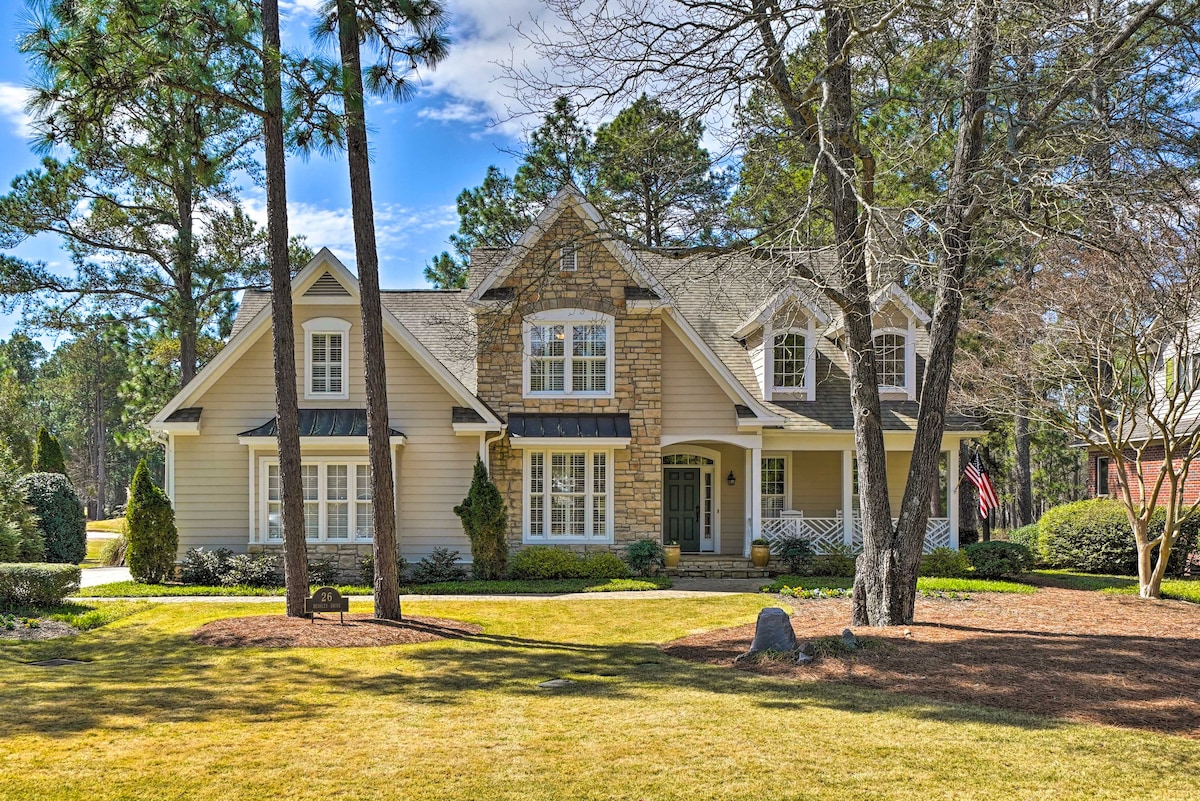 A spacious and charming two-story home features a blend of stone and siding exterior. The front yard presents well-manicured lawns and shrubs, framed by tall trees. Light clouds drift above, adding to the inviting outdoor setting.