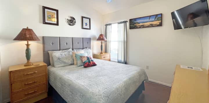 חדר שינה 2 ממוקם במרכז הימני וכולל מיטת קווין סייז, מאוורר תקרה, טלוויזיה עם מסך שטוח וארון הזזה.